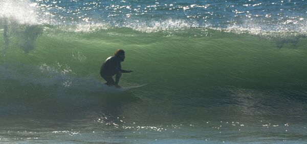 Kleiner Surfer in grüner Welle in den besten surfspots spanien