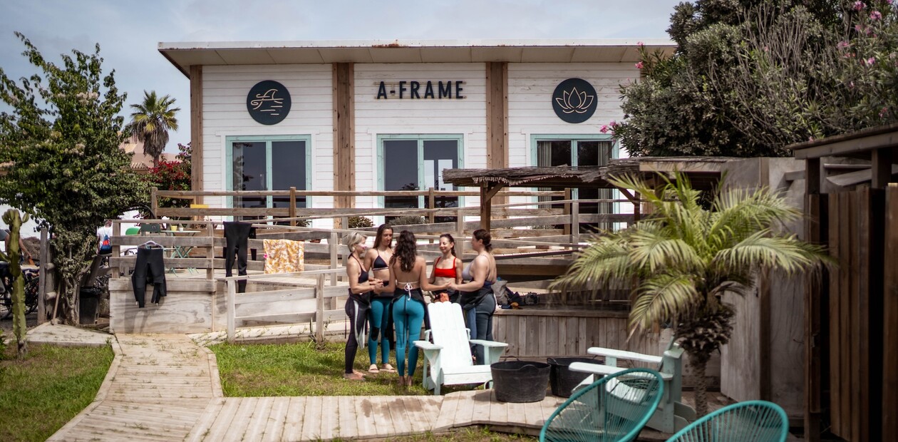 Gruppe von Surfern bereitet sich auf dem Rasen vor dem A-Frame Camp vor