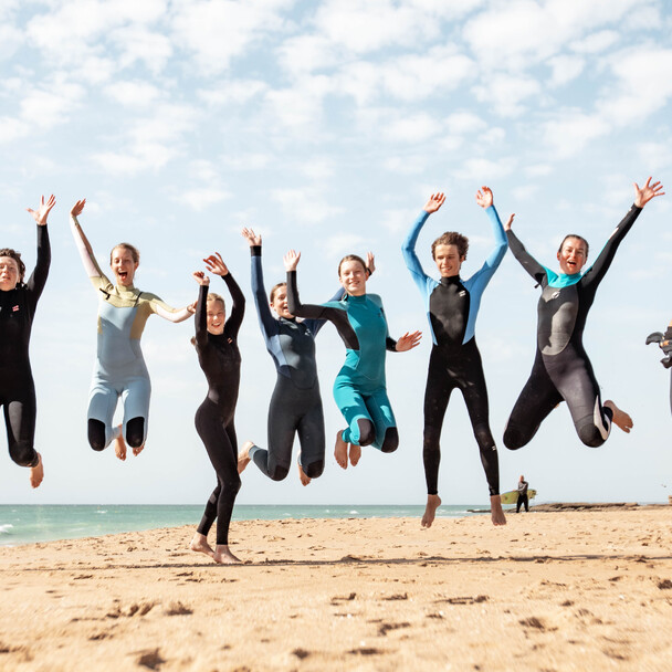 Surfer springen nach der Surfsession im Neoprenanzug am Strand