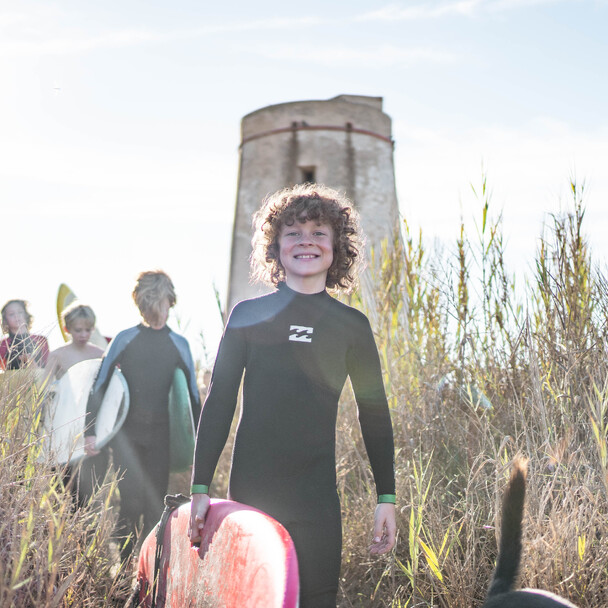 Kids walking down beach with surfboards in southern Spain