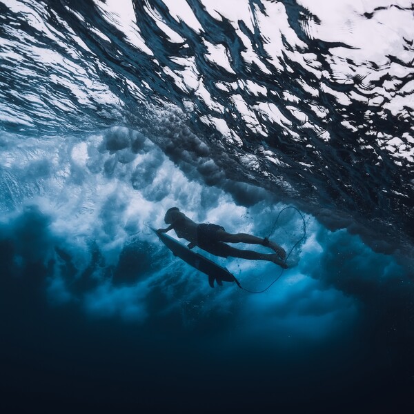 Surfer taucht beim Duck Dive unter eine brechende Welle
