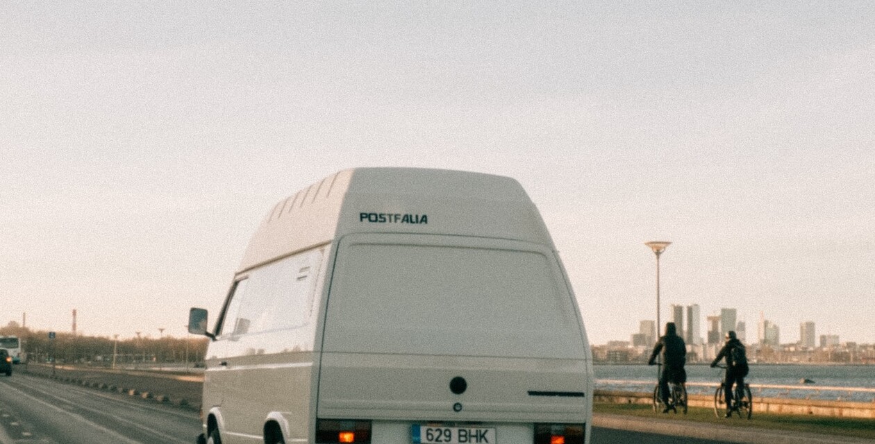 Weißer VW-Bus fährt bei Sonnenuntergang auf der Autobahn