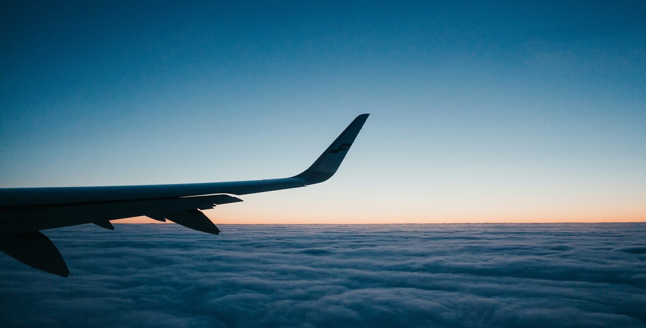 Flugzeugflügel bei Sonnenaufgang über den Wolken aus dem Passagierfenster