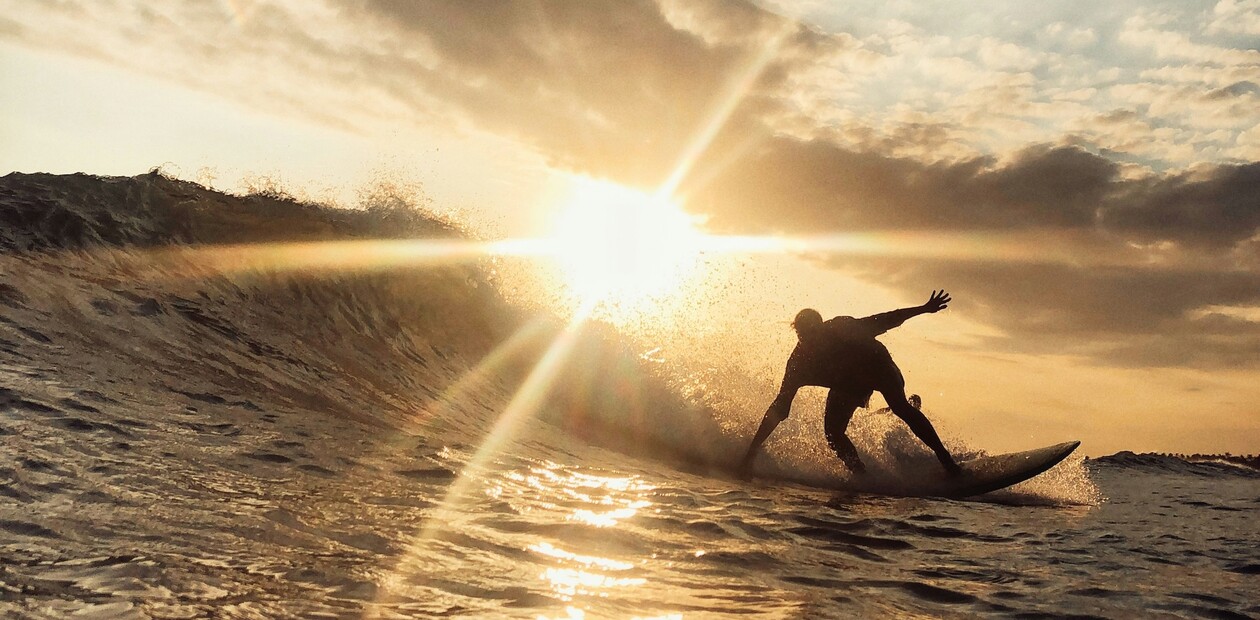 Silhouettierter Surfer reitet mit Sonne im Rücken in Richtung Kamera