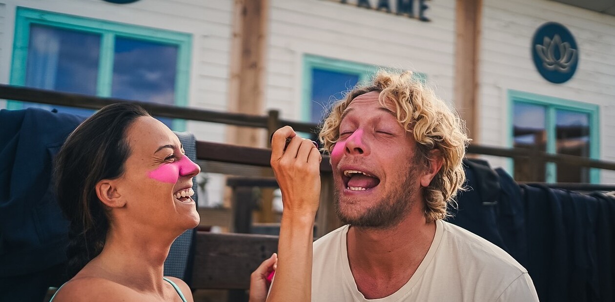 Weiblicher Gast trägt einer anderen Person pinkes Zink im Surfcamp auf