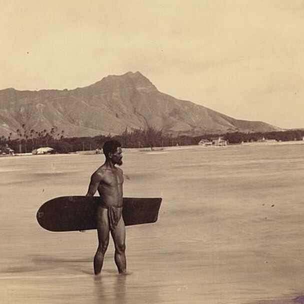 Ein Hawaiianer mit einem traditionellen Holz-Surfbrett