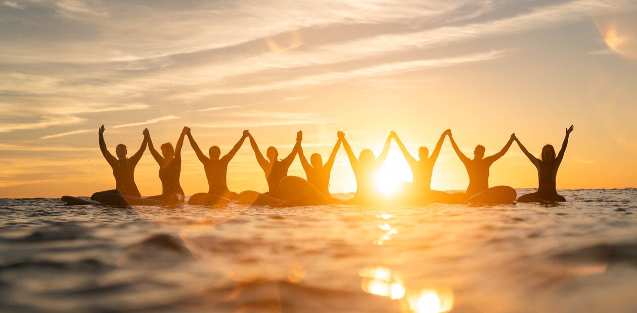 Surfer mit erhobenen Händen bei Sonnenuntergang