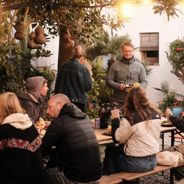 Gruppe isst und unterhält sich nach dem Surfen im Garten von A-Frame