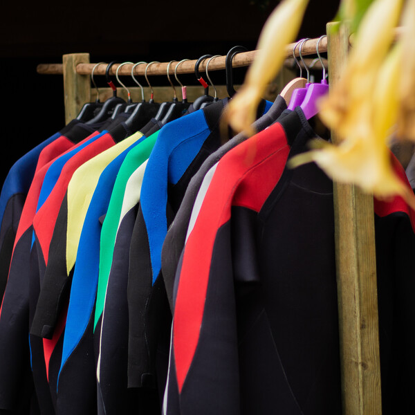 Washing wetsuits, wetsuits hanging next to each other