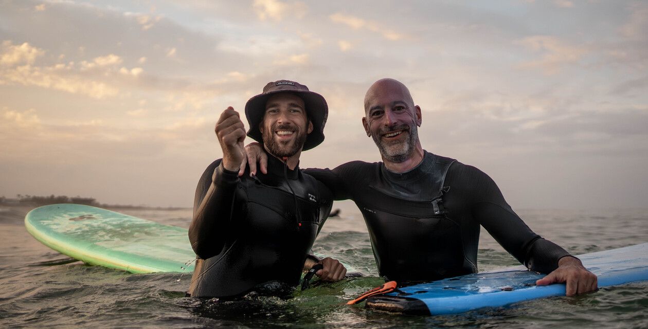 Surfer mit Neoprenanzug - gehört auf die Packliste für Surfurlaub