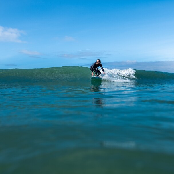 Male surfer on soft-top surfs a right-hand wave
