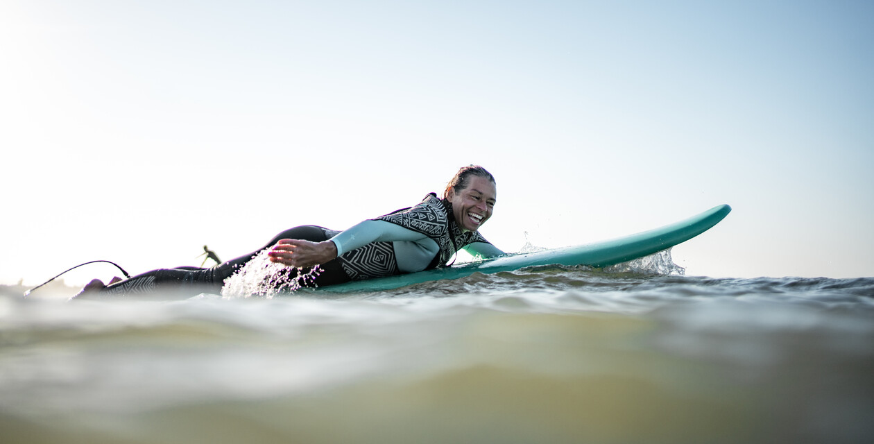 Frau genießt Sonne im Gesicht beim Surf Yoga Retreat