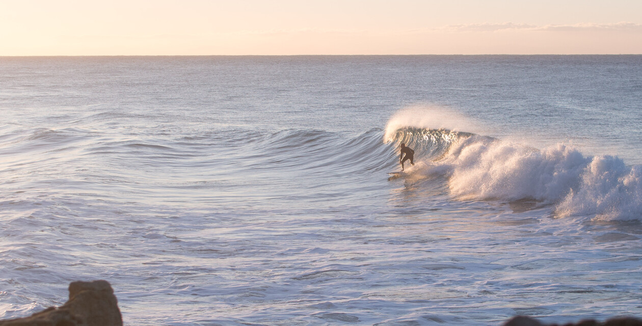 surfboard kaufen, mann mit surfbrett am strand