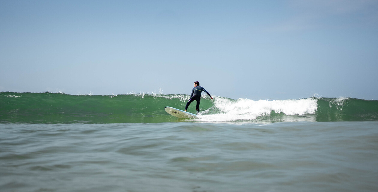 Surfer in grüner Welle im Surfcamp Andalusien