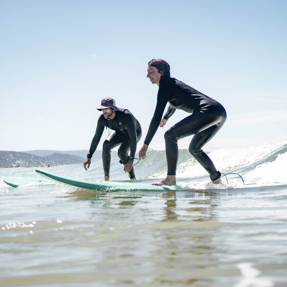 Surflehrer mit Schülerin im Wasser, Surfcamps für Erwachsene