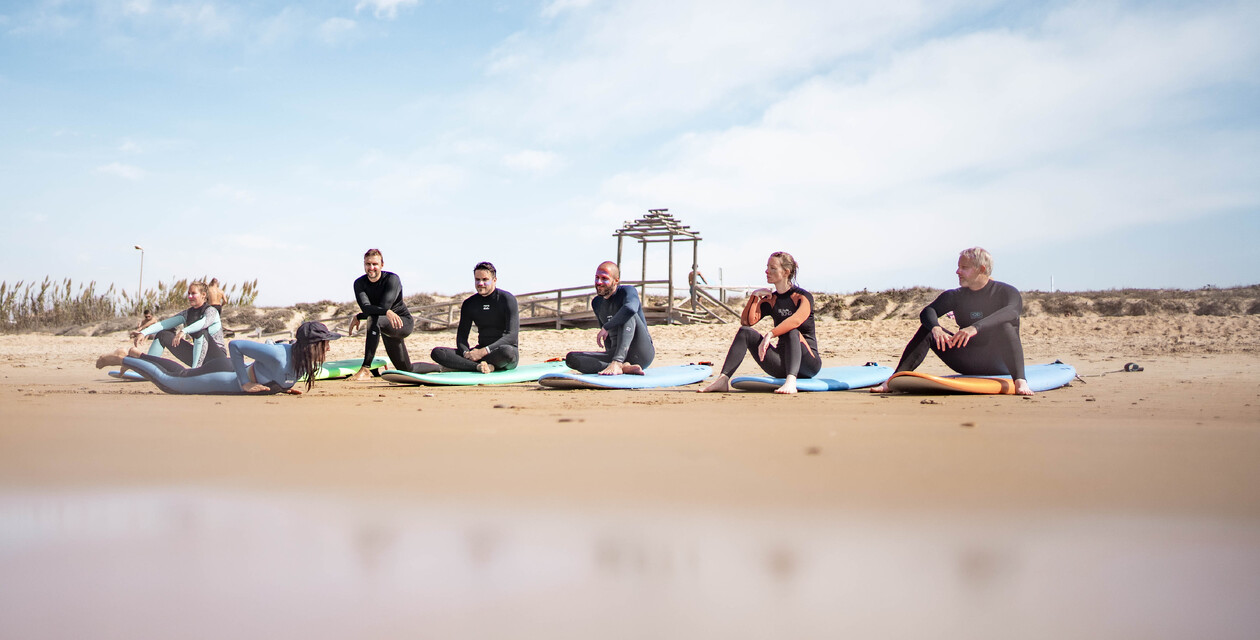 Menschen sitzen auf Surfbrettern am Strand, Surfcamps für Erwachsene