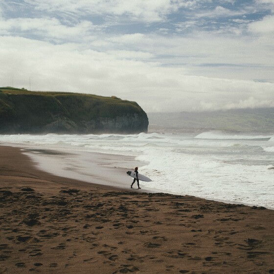 Surfen auf Madeira, Surfer läuft ins Wasser, leerer Strand