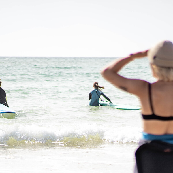 Weibliche Surflehrerin beobachtet Schüler beim Üben im flachen Wasser