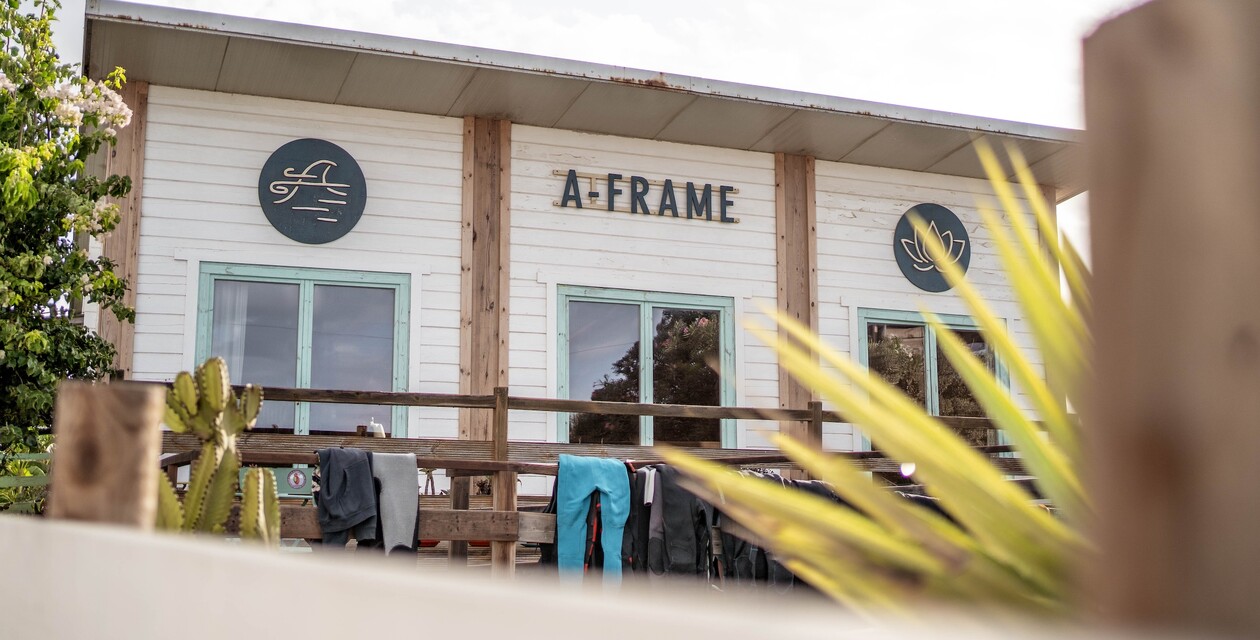 A-Frame-Fassade mit Neoprenanzügen, die in der Sonne auf Stangen trocknen
