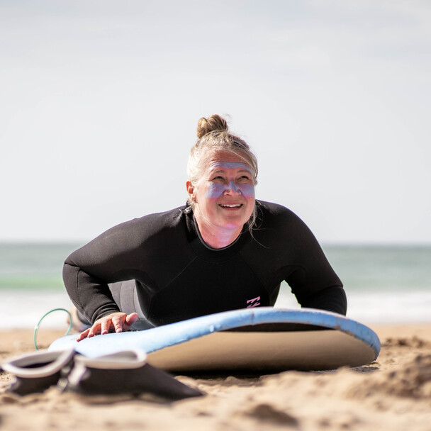 Surferin liegt am Strand auf dem Surfbrett und wartet auf Anweisungen