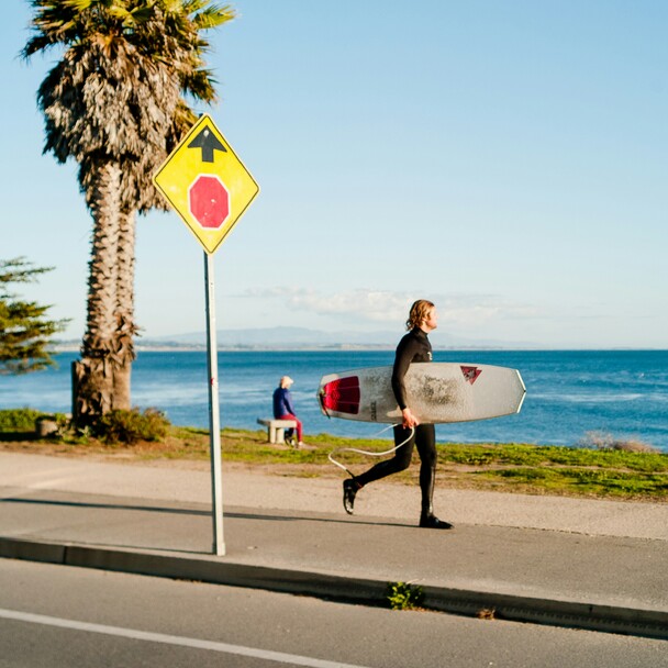 Surfer with leash & surfboard by the sea