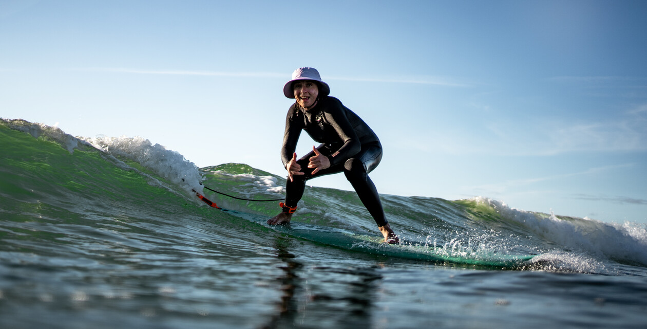 Surferin mit Hut in grüner Welle