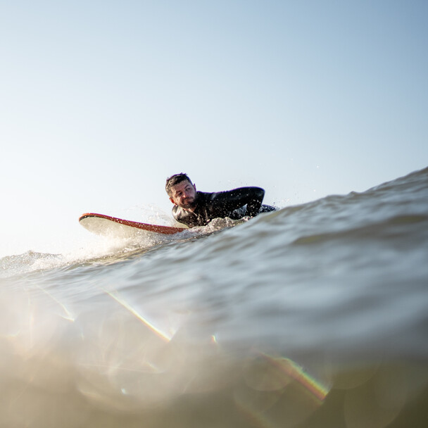 Surfer liegt auf Surfboard, Surfkurs