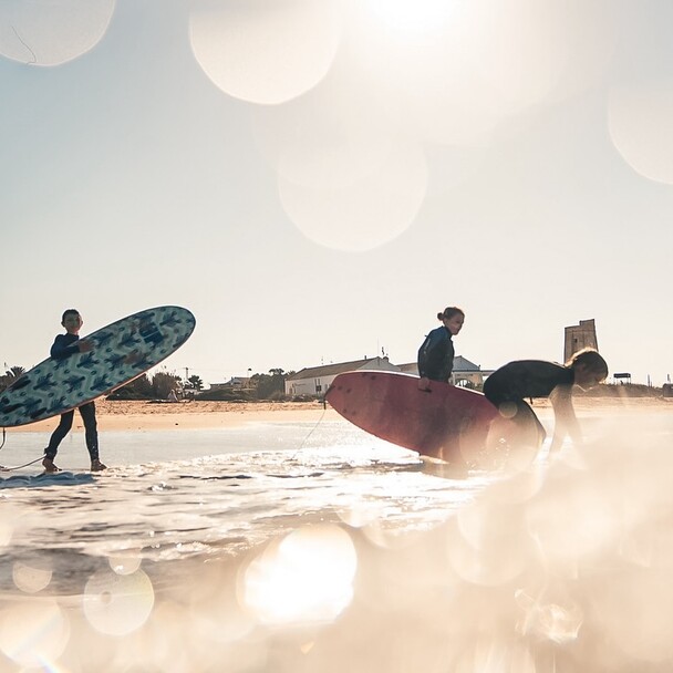 Surfer im Sonnenuntergang am Strand, Surfkurs