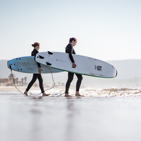 Two women with surfboards under their arms in a surf course