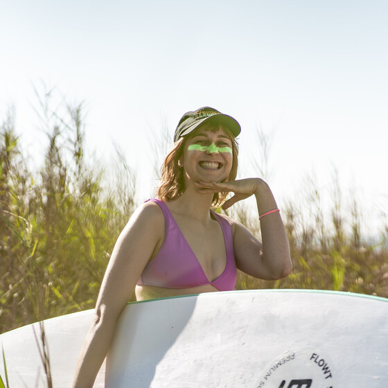 Surferin mit Surfbrett unterm Arm im Surfkurs