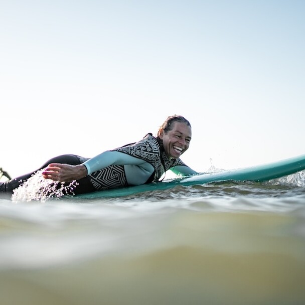 Surferin paddelt und lächelt in die Kamera