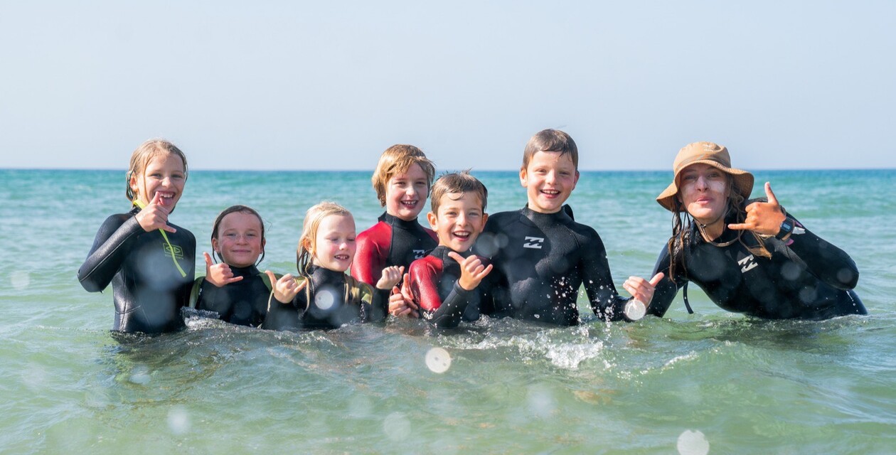 Kinder in Neoprenanzügen lächeln in die Kamera