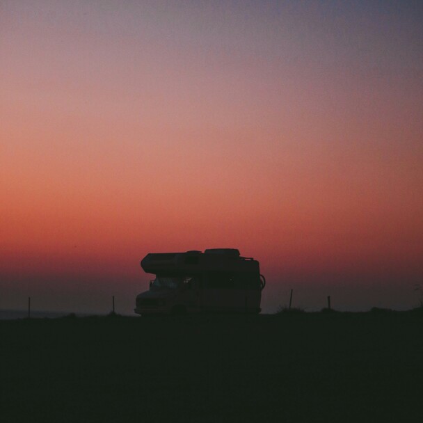Van als Silhouette vor leuchtendem Sonnenuntergang auf dem Weg nach El Palmar