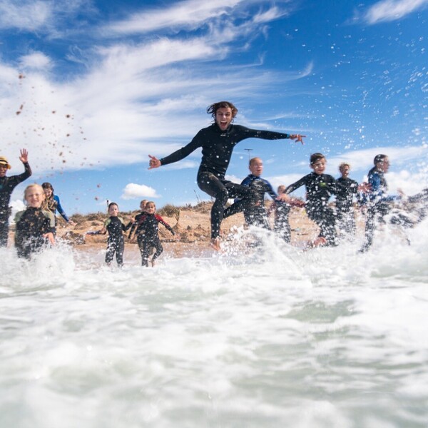 Surfcamps für Familien, Kinder im Wasser spielend im Neoprenanzug