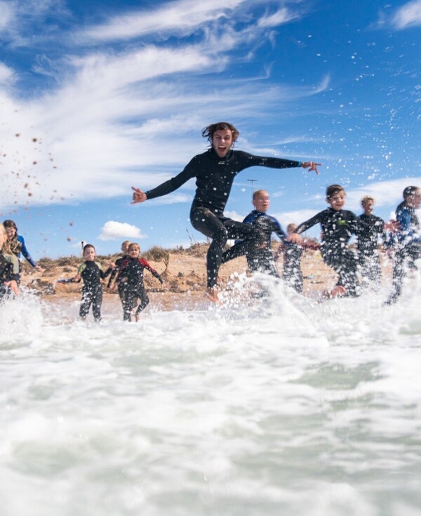 Surfcamps für Familien, Kinder im Wasser spielend im Neoprenanzug