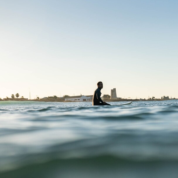 Kundestimme zum Surfen im A-Frame Surfcamp in Andalusien, Mann auf Surfbrett im Wasser
