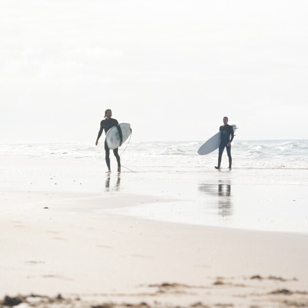 Surfcamps Spanien, A-Frame in El Palmar, zwei Surfer kommen aus dem Wasser vom Wellenreiten