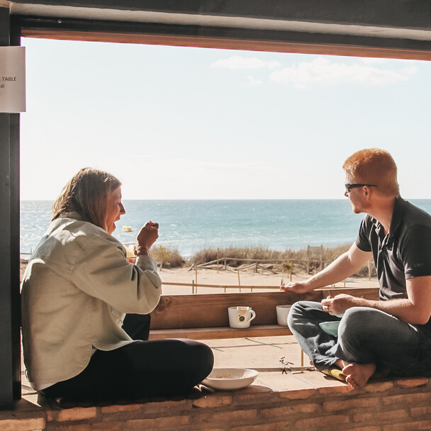 Surfurlaub Spanien mit Blick auf's Meer, zwei Personen essen und genießen den Ausblick