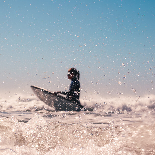 Surfcamps Spanien, A-Frame Kundenstimme, Surferin mit Surfbrett im Wasser
