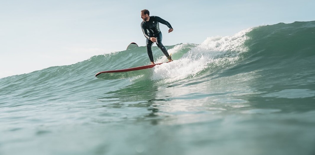 learn to surf in the sea, surfer in the water, drone shot