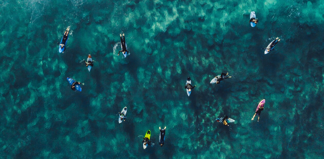 learn to surf in the sea, surfer in the water, drone shot