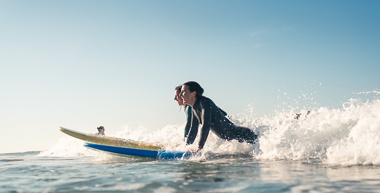 Zwei Surfer nebeneinander im Weißwasser, Surfen lernen