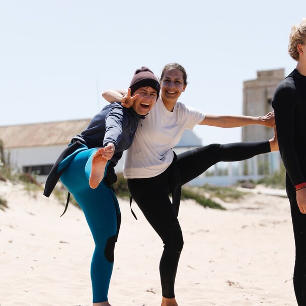 Surfen lernen Erwachsene, Erwachsene im Neoprenanzug machen Spaß am Strand