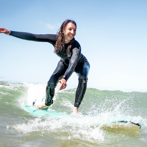 Surfen lernen im Urlaub, Frau auf Softboard, lächelnd