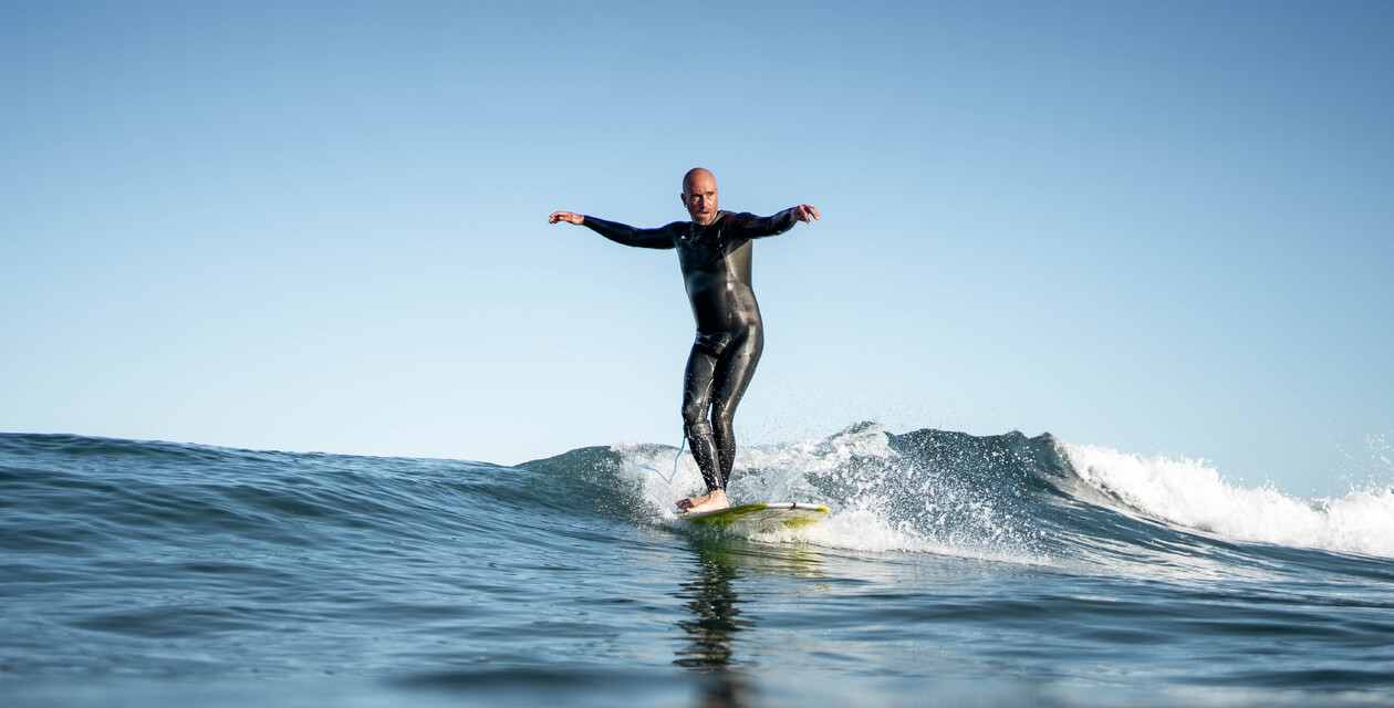 Longboard Surfer in Welle beim Surfen lernen