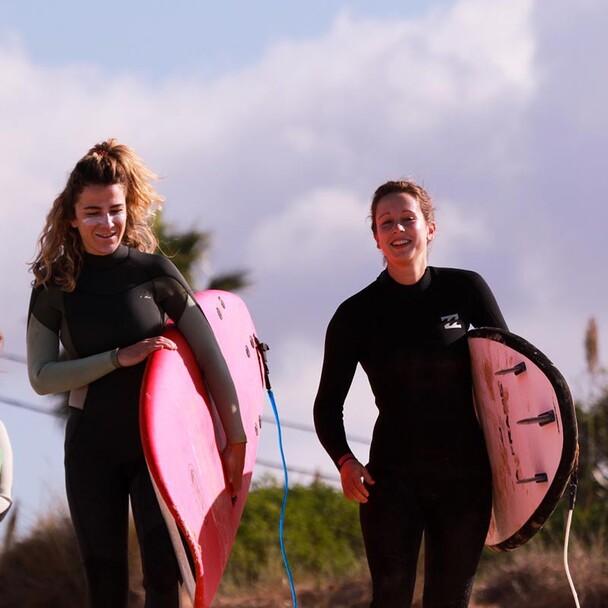 Surf holiday beginners carry the board to the beach