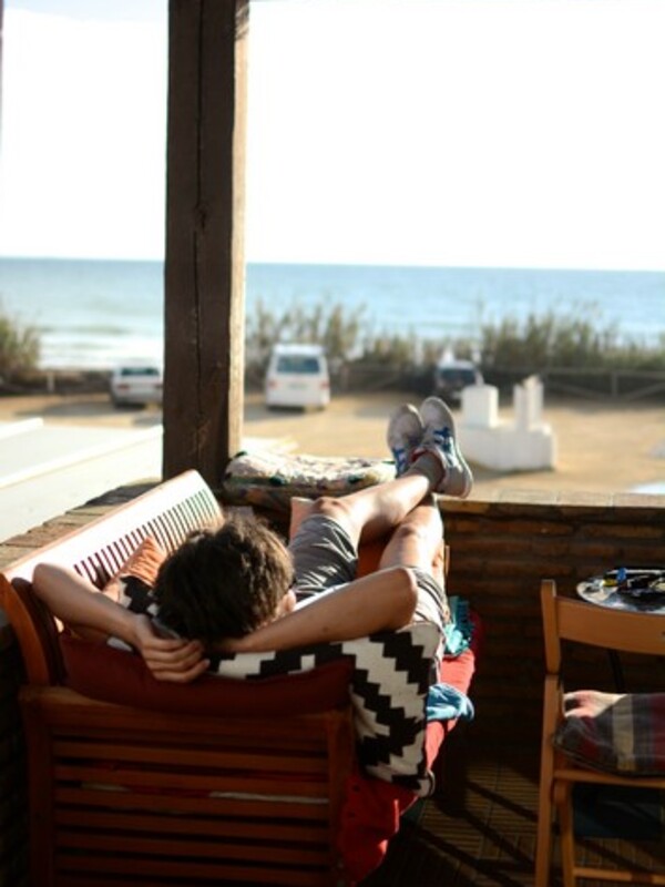 Surf camp Andalusia, man looks directly at the sea from the couch